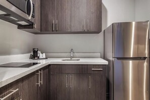 A modern kitchen with dark wood cabinets, a stainless steel refrigerator, and a built-in microwave.
