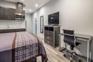 A modern hotel room with a bed, a desk, a television, and a microwave.