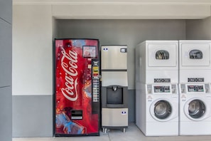 A vending machine with a Coca-Cola logo, a water dispenser, and a stack of washing machines.