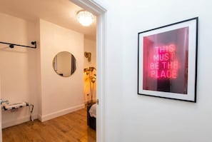 A hallway with a framed motivational quote, a round mirror, and a chandelier. - East Dulwich 2BR Flat w/ Garden & Driveway Parking (London)