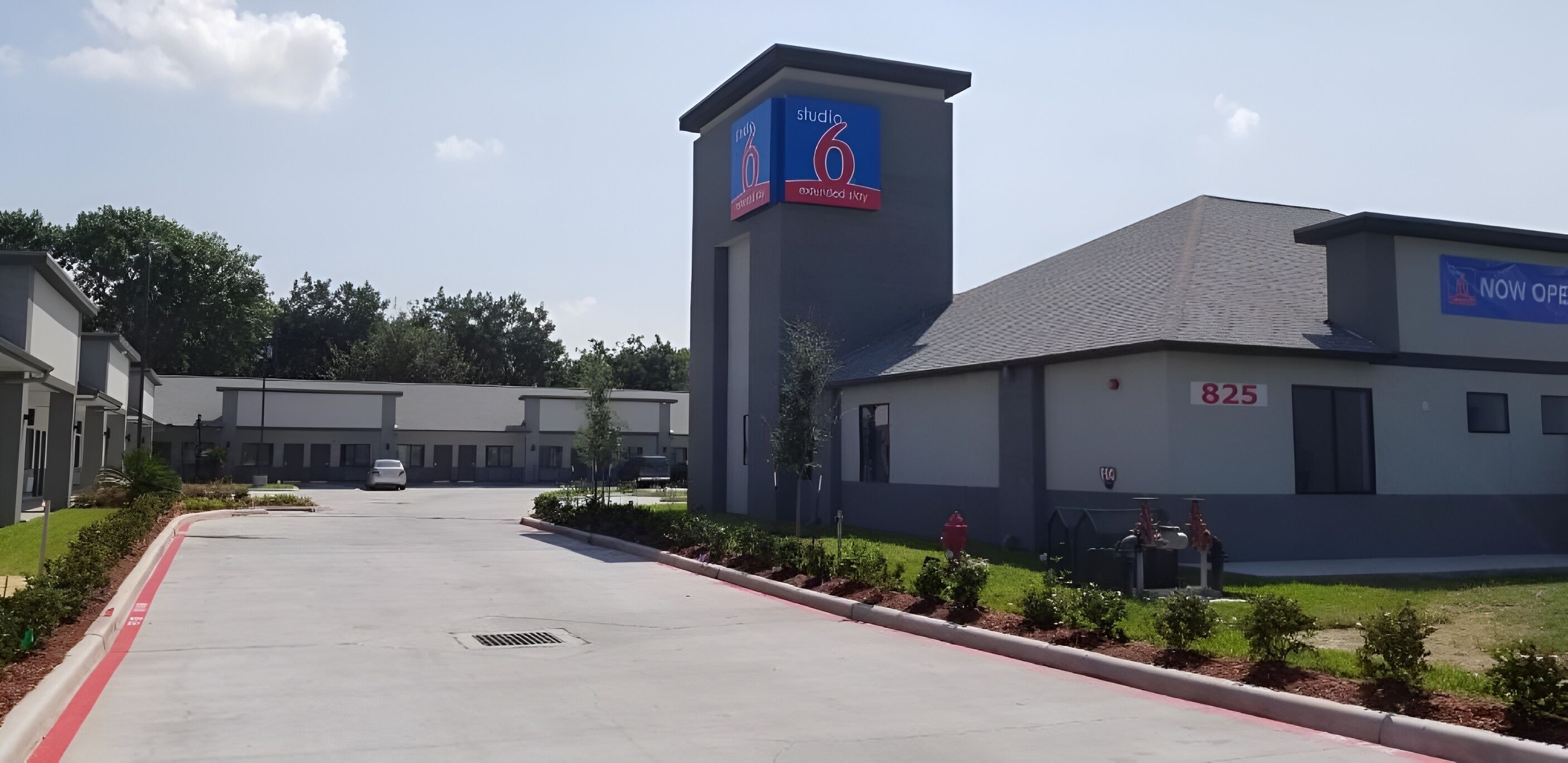 A modern building with a prominent tower displaying a clock and a sign indicating it's a studio hotel.