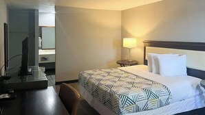 A hotel room with a bed, bedside table, lamp, and a desk with a computer. - Studio King Unit | Close to Hutchinson County Museum - 0.9 miles (Borger)
