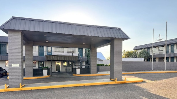 A gas station with a canopy, a car wash, and a building with multiple windows in the background.