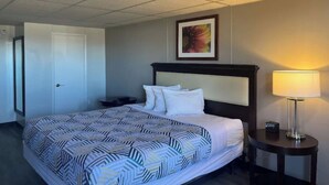 A hotel room with a bed, a nightstand, a lamp, and a framed picture on the wall.