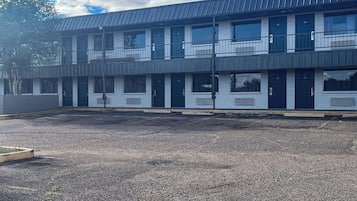 Een meerhoog gebouw met een plat dak, grote ramen en een parkeerplaats ervoor.