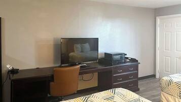 Een hotelkamer met een bureau, een televisie, een stoel en twee bedden.