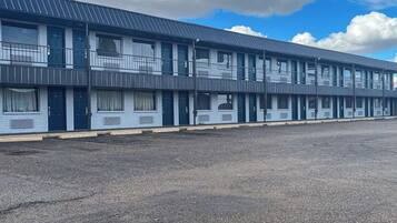A multi-story motel with a flat roof and a parking lot in front.
