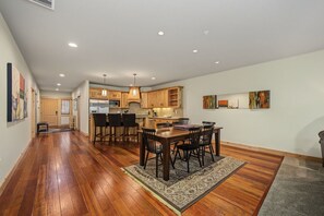 A spacious kitchen with wooden cabinets, a dining area with a table and chairs, and a hallway with hardwood flooring. - Zigzag River Condo 102 at South Grand Lodge | Private Balcony (Government Camp)