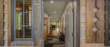 A hallway with a wooden door labeled '102' leading to a room with a window and a bench.