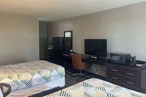 A hotel room with two beds, a desk, a chair, a television, and a microwave.