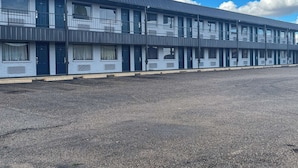 A multi-story motel with a flat roof and a parking lot in front.