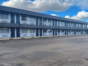 A multi-story motel with a flat roof and a parking lot in front.