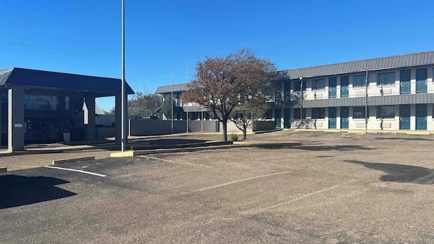 A parking lot with a building that has multiple windows and a flat roof.