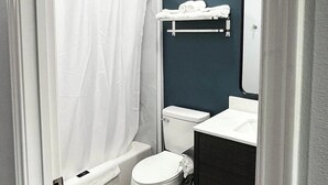 Une salle de bain avec des toilettes blanches, une baignoire, un lavabo et un porte-serviettes.