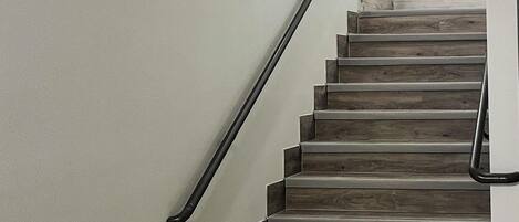 Una escalera de madera con barandilla negra que da a una plataforma.