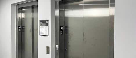 Two elevator doors with emergency instructions and floor indicators.