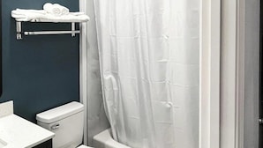 Ein Badezimmer mit Toilette, Waschbecken, Duschvorhang und Handtuchhalter.