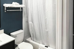 A bathroom with a toilet, a sink, a shower curtain, and a towel rack. - Budget & Pet-Friendly Room | Free Parking | Clear Creek Golf Club - 3.9 miles (Houston)