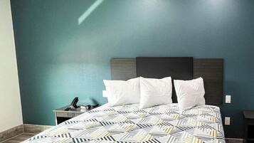 Una habitación de hotel con cama, mesita de noche y escritorio.