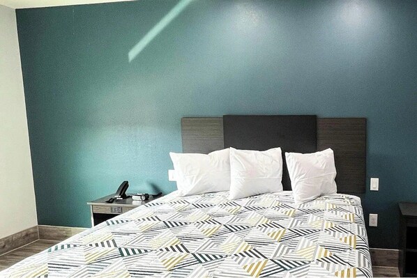 A hotel room with a bed, a nightstand, and a desk. - Budget & Pet-Friendly Room | Free Parking | Clear Creek Golf Club - 3.9 miles (Houston)