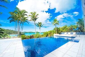 A swimming pool with a view of the sea and palm trees. - Baybliss Escape #4 - Adults Only (Shute Harbour)