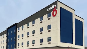 A multi-story building with a prominent 'studio 6' sign, featuring a modern architectural design with a mix of beige and blue facade, multiple windows, and a flat roof. - 2 Queen Beds | 2 Miles to Little Caesars Pizza | Free Parking | Pet-Friendly (Houston)