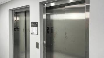 Dos puertas de ascensor con instrucciones de emergencia e indicadores de planta.