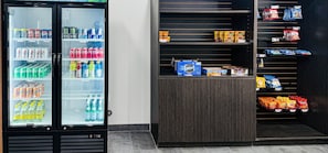 A vending machine with various drinks and snacks, a shelf with packaged goods, and a dark wooden counter.