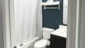 Une salle de bain avec des toilettes blanches, une baignoire, un lavabo et un porte-serviettes.