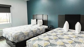 Une chambre d’hôtel avec deux lits, une fenêtre et un mur d’accent de couleur bleu-vert foncé.