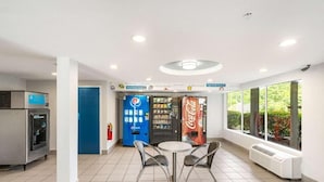 A clean, well-lit indoor area with vending machines, a table with chairs, and large windows. - Augusta King Room w/ Kitchenette Near Riverwalk Entertainment (Augusta)