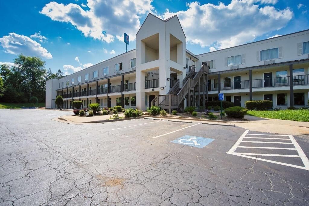 A multi-story hotel with a central atrium, outdoor parking, and a wheelchair-accessible area.