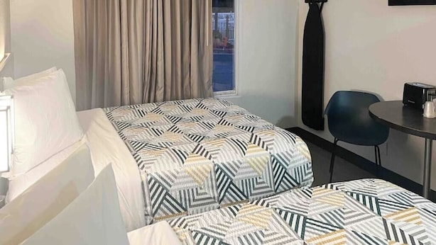 A hotel room with a bed, a chair, a table, a window with curtains, and a wall-mounted item. - Extended Stay w/ Kitchen Near Augusta Mall and Downtown Attractions (Augusta)