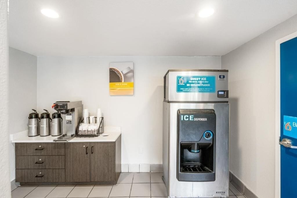A hotel room with a kitchenette, a water dispenser, and a coffee machine.