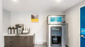 A hotel room with a kitchenette, a water dispenser, and a coffee machine.