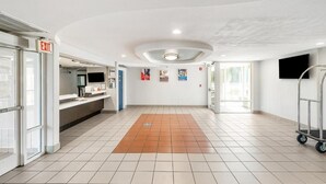 A spacious lobby with a tiled floor, an exit sign, a reception desk, and a cart. - Extended Stay w/ Kitchen Near Augusta Mall and Downtown Attractions (Augusta)