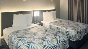 A hotel room with two beds, each with a patterned bedspread, a nightstand with a lamp, and a headboard. - Extended Stay w/ Kitchen Near Augusta Mall and Downtown Attractions (Augusta)