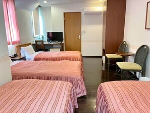 A hotel room with two beds, a desk with a computer, a TV, and a seating area with chairs. - Vrbo Property (伊東市)