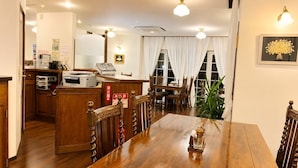 Habitación de hotel con una mesa de comedor de madera, una recepción y un amplio ventanal con cortinas.