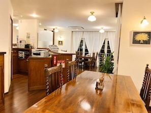 A hotel room with a wooden dining table, a reception desk, and a large window with curtains. - Vrbo Property (伊東市)