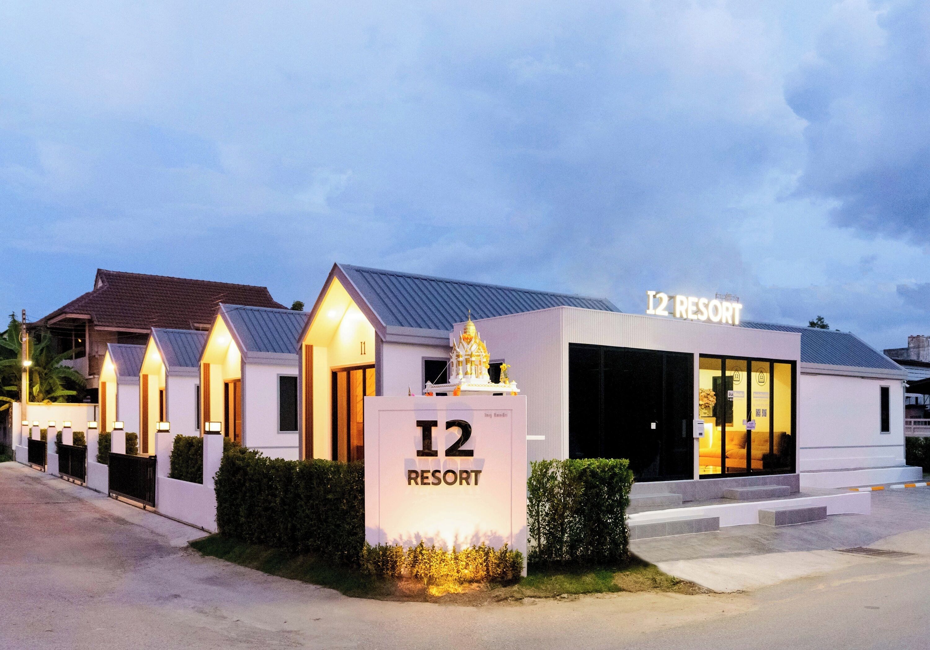 Edificio de un complejo turístico con un cartel que indica 'I2 RESORT' y una entrada amplia.