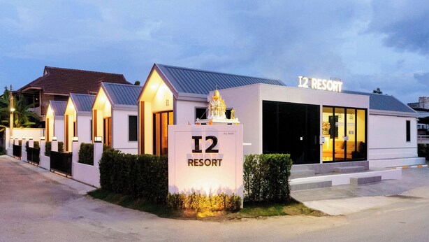 Edificio de un complejo turístico con un cartel que indica 'I2 RESORT' y una entrada amplia.