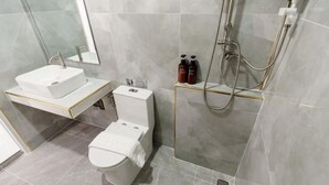 Un baño moderno con lavamanos, inodoro y ducha blancos.