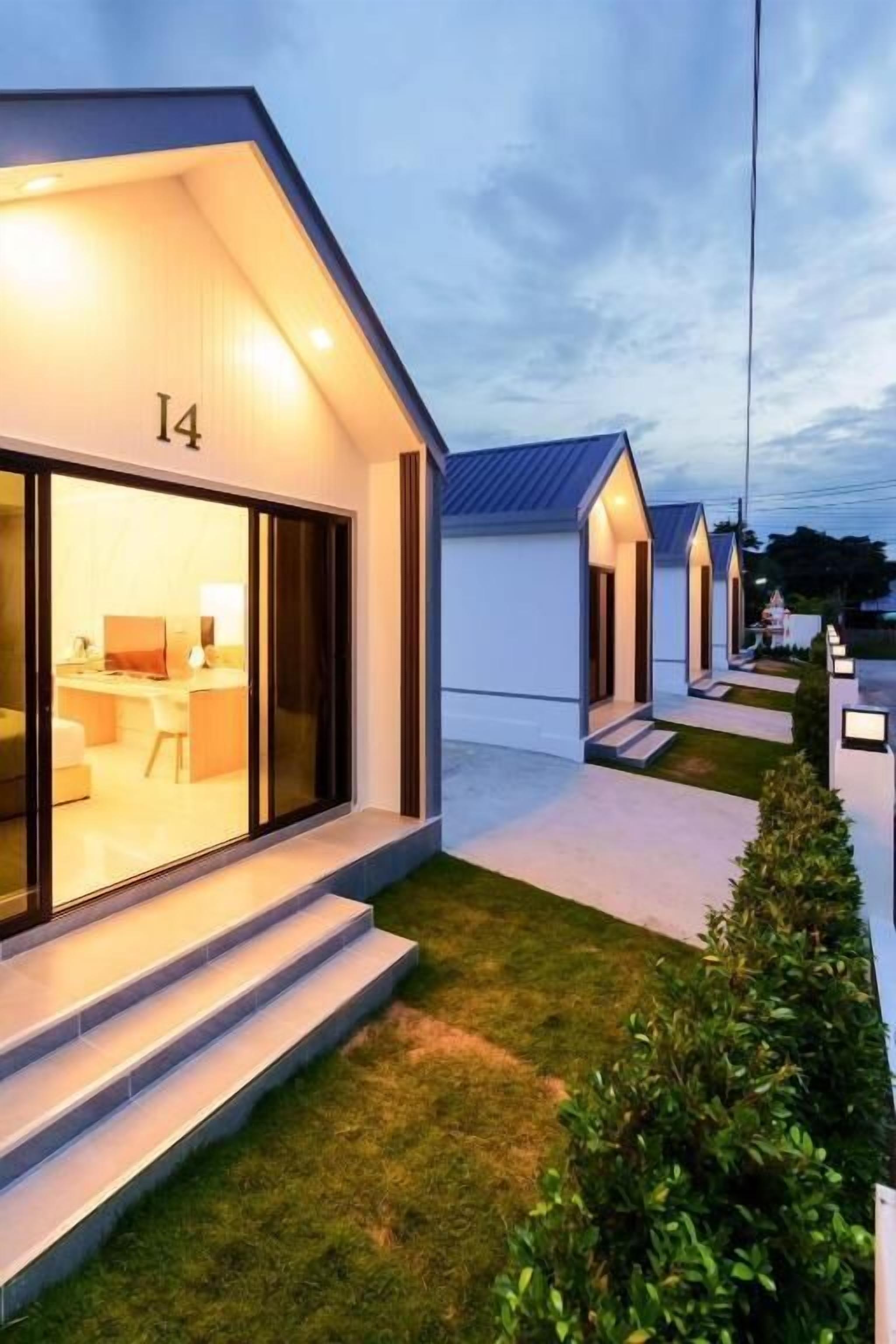 Un hotel moderno con una entrada bien iluminada, el número 14 visible y un área exterior limpia y ajardinada.