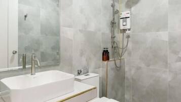 A modern bathroom with a white sink, mirror, and toilet.
