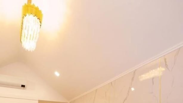 Una habitación de hotel moderna con cama, escritorio, televisor y un espejo grande.