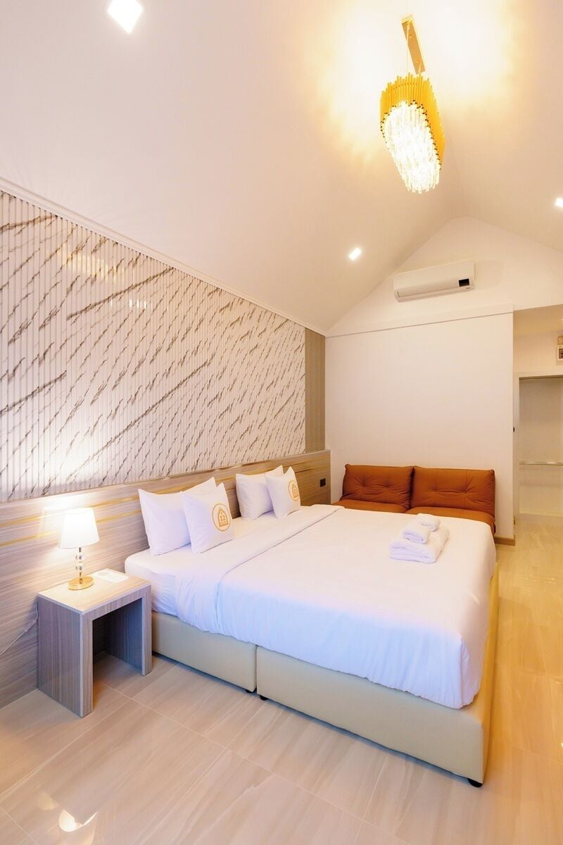 Una habitación de hotel moderna con una cama grande, una mesita de noche, una lámpara y un papel tapiz estampado.