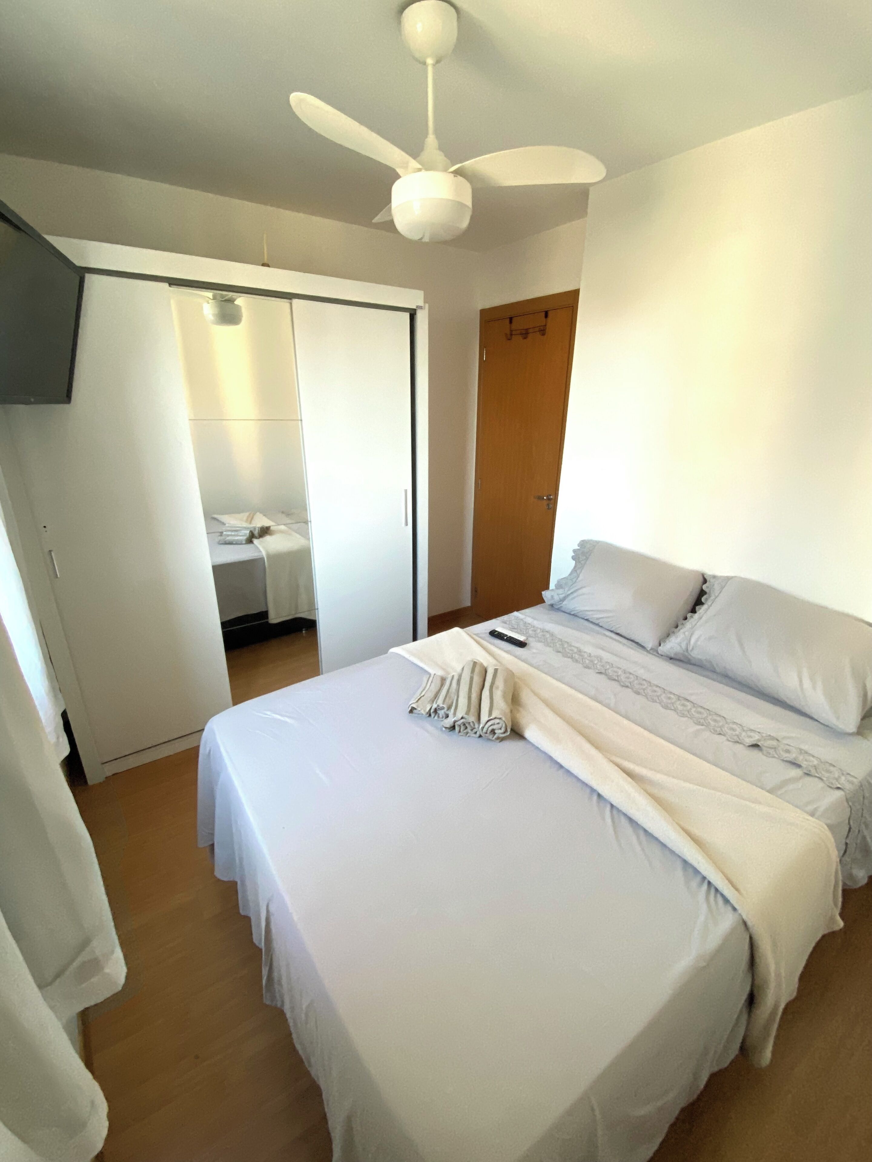 Une chambre à coucher avec un lit, un ventilateur de plafond, une armoire et une porte.