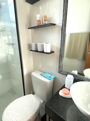 A bathroom with a toilet, a sink, a mirror, and a shower area. - Apartment near Galeão Airport • 2 bedrooms • With 1 vacancy (Duque de Caxias)