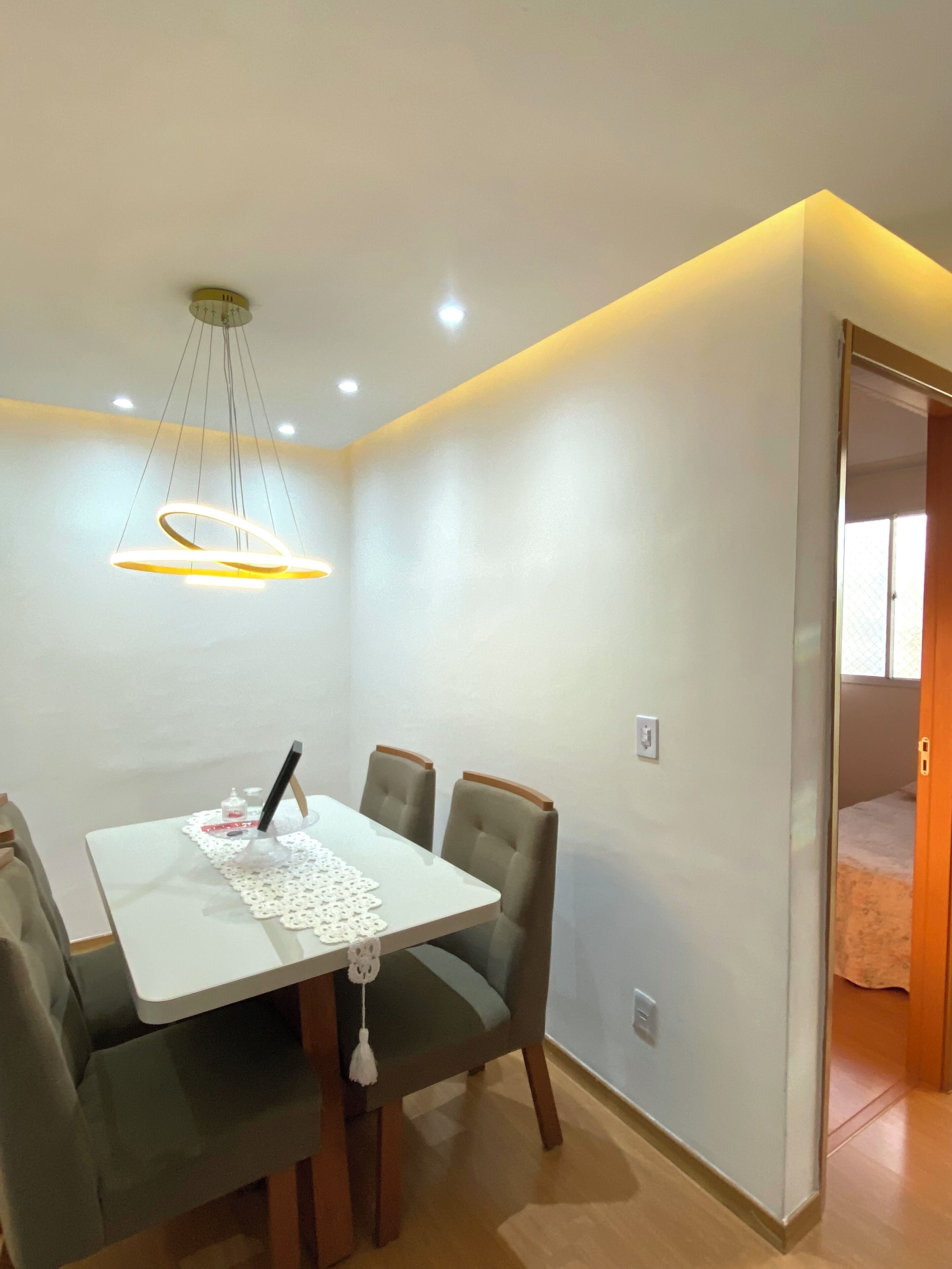 A dining area with a table and chairs, a pendant light, and a door leading to another room.